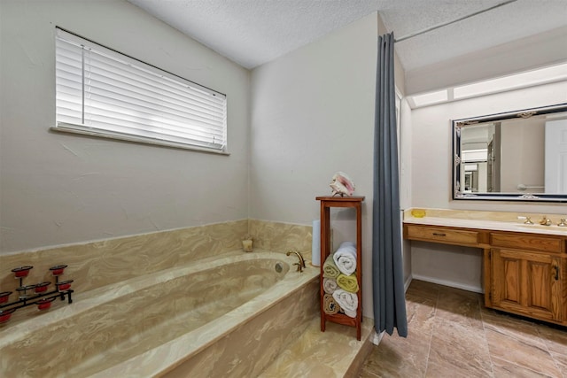 full bathroom featuring vanity, a garden tub, and a textured ceiling