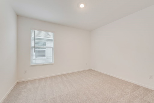 spare room with recessed lighting, light colored carpet, and baseboards