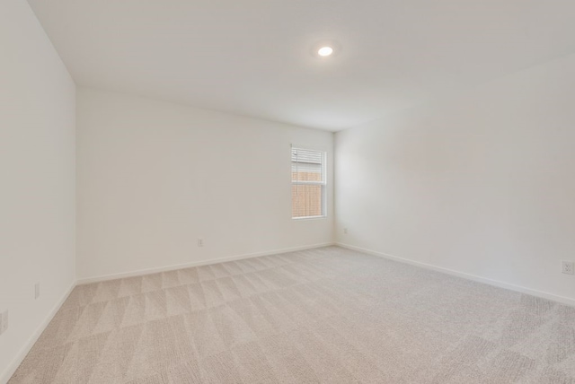 empty room featuring recessed lighting, light colored carpet, and baseboards