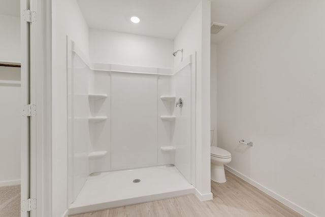 bathroom with visible vents, baseboards, toilet, a stall shower, and wood finished floors