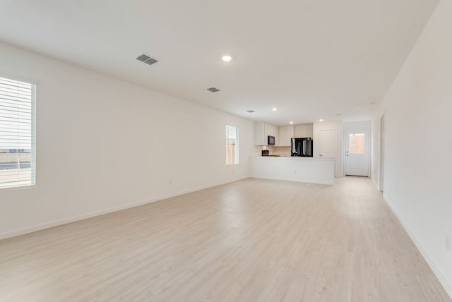 unfurnished living room with light wood finished floors, visible vents, recessed lighting, and baseboards