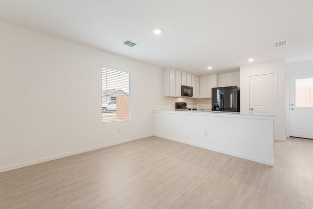 kitchen featuring baseboards, visible vents, light wood-style flooring, black appliances, and light countertops