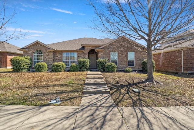 single story home featuring brick siding and a shingled roof