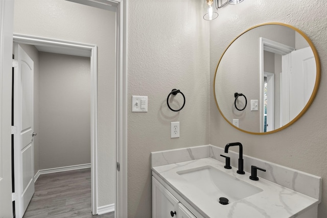 bathroom with wood finished floors, vanity, and a textured wall