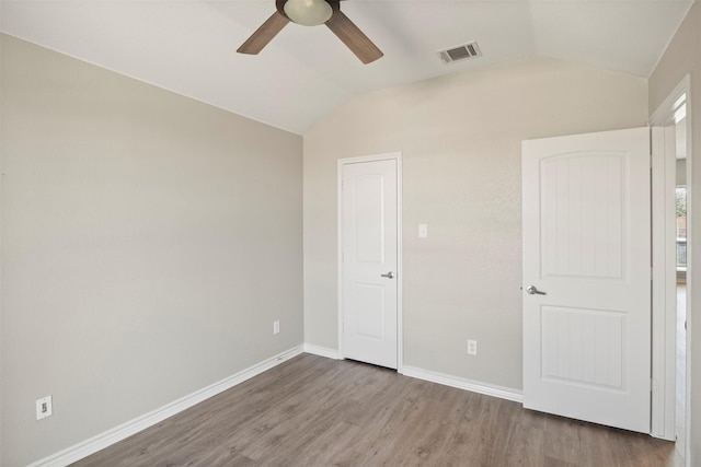 unfurnished bedroom with visible vents, baseboards, lofted ceiling, and wood finished floors