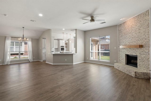 unfurnished living room with plenty of natural light, ceiling fan with notable chandelier, and visible vents