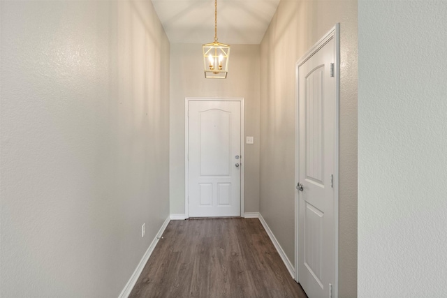 doorway to outside with dark wood-style floors, baseboards, and a chandelier