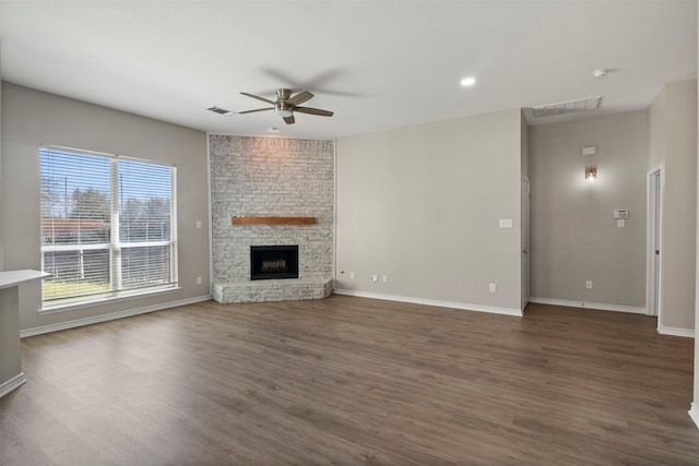 unfurnished living room featuring visible vents, dark wood-type flooring, a fireplace, baseboards, and ceiling fan