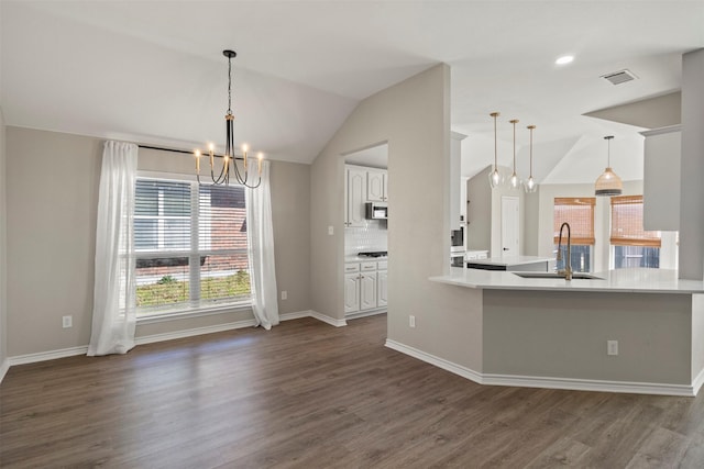 kitchen with visible vents, dark wood-style flooring, a sink, vaulted ceiling, and a chandelier