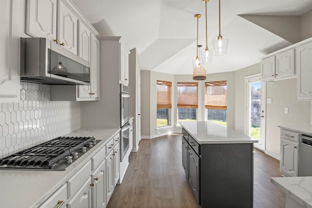 kitchen featuring vaulted ceiling, white cabinets, a center island, and stainless steel appliances