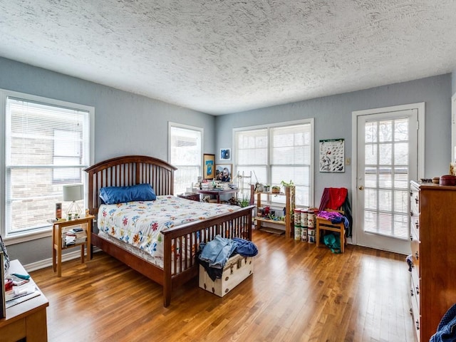 bedroom with multiple windows, wood finished floors, and a textured ceiling