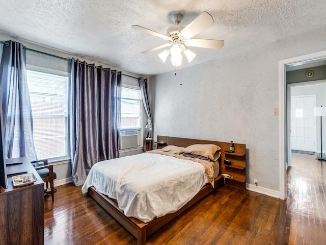 bedroom featuring hardwood / wood-style floors, cooling unit, baseboards, a textured ceiling, and a textured wall