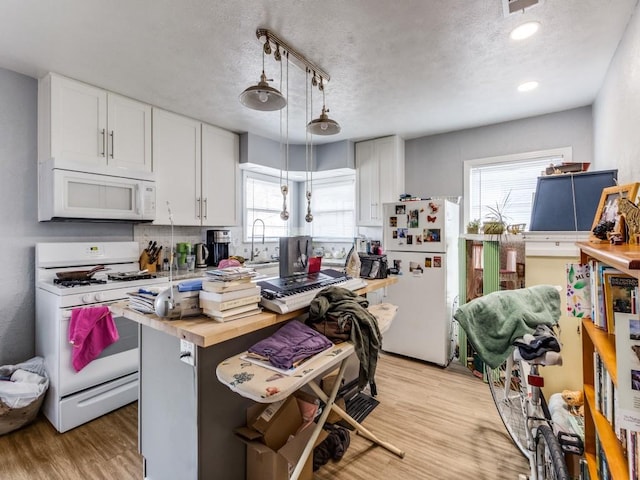 kitchen featuring a wealth of natural light, white appliances, light wood-style floors, and butcher block counters