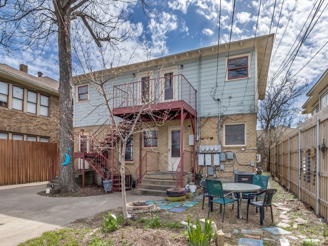 back of house featuring a balcony and fence