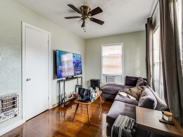 living area featuring a ceiling fan, heating unit, a textured ceiling, hardwood / wood-style floors, and cooling unit