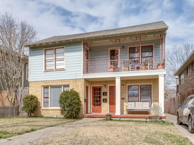 view of front of house with fence, a porch, a front yard, roof with shingles, and a balcony