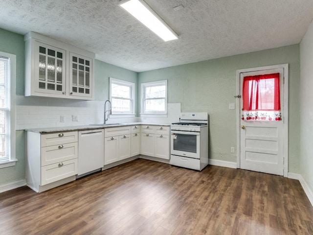 kitchen with a sink, glass insert cabinets, white cabinets, white appliances, and dark wood-style flooring