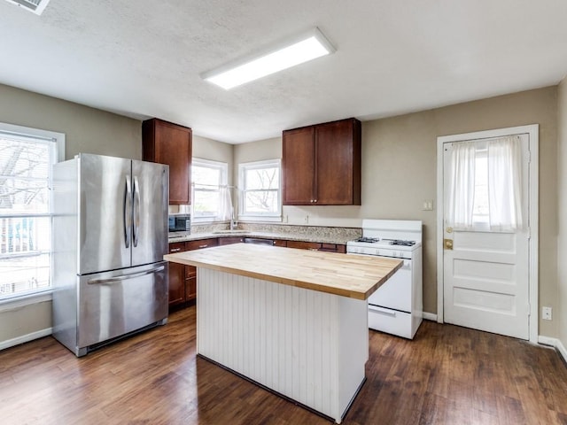 kitchen featuring wooden counters, a center island, dark wood-type flooring, appliances with stainless steel finishes, and a textured ceiling