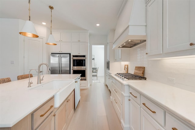 kitchen with a sink, appliances with stainless steel finishes, light countertops, decorative backsplash, and custom exhaust hood