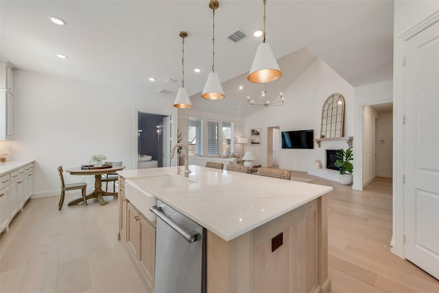 kitchen featuring visible vents, light wood-type flooring, vaulted ceiling, stainless steel dishwasher, and a sink