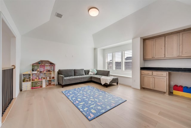 living area with visible vents, lofted ceiling, and light wood finished floors