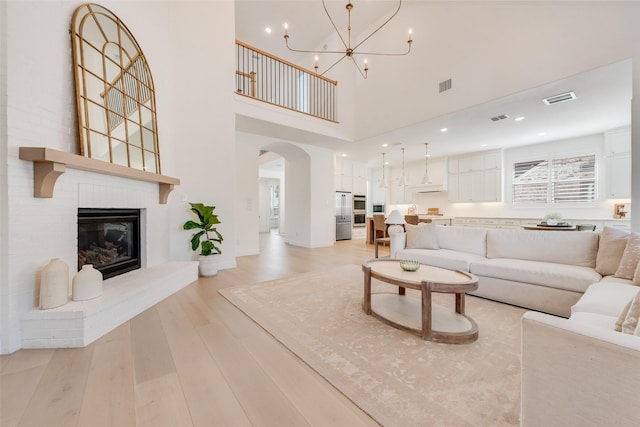 living room featuring visible vents, arched walkways, and light wood-style flooring