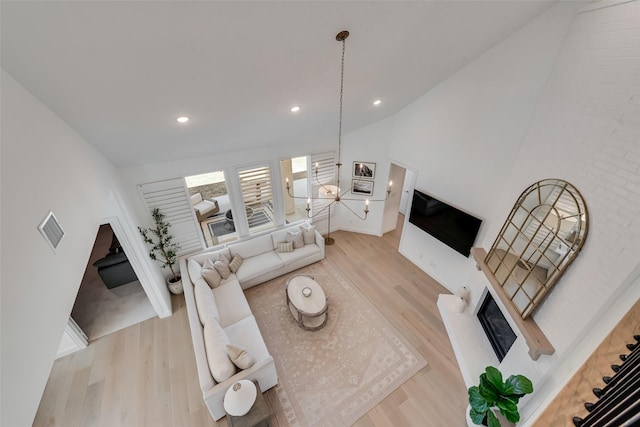 living room featuring wood finished floors, visible vents, high vaulted ceiling, recessed lighting, and a glass covered fireplace