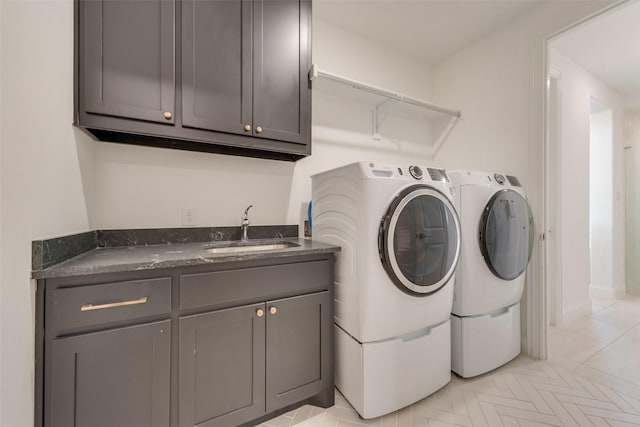 washroom with a sink, cabinet space, light tile patterned floors, and washing machine and clothes dryer