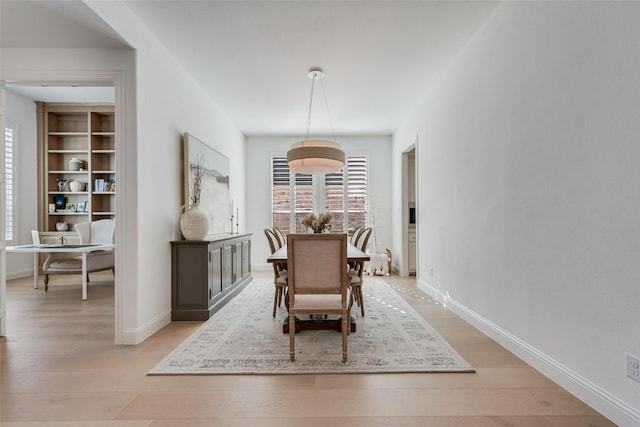 dining space with light wood-style flooring and baseboards