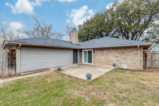 rear view of property featuring fence, a chimney, a lawn, a patio area, and brick siding