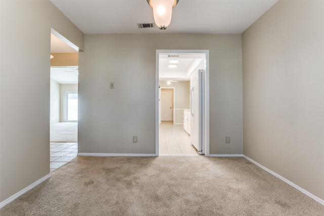 spare room featuring visible vents, baseboards, light colored carpet, and ceiling fan