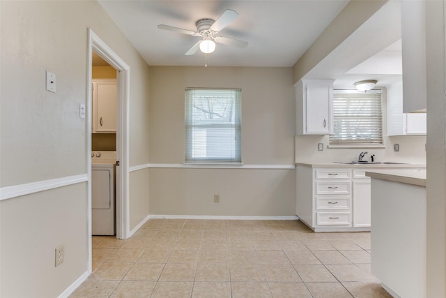 kitchen featuring a ceiling fan, a healthy amount of sunlight, washer / dryer, light countertops, and white cabinetry