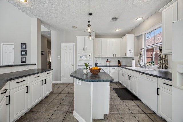 kitchen with white appliances, visible vents, a sink, dark countertops, and backsplash