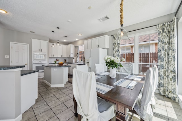 dining space with light tile patterned flooring, recessed lighting, visible vents, and a textured ceiling