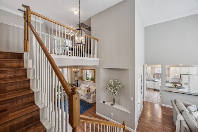 stairs with a chandelier, a high ceiling, and a wealth of natural light