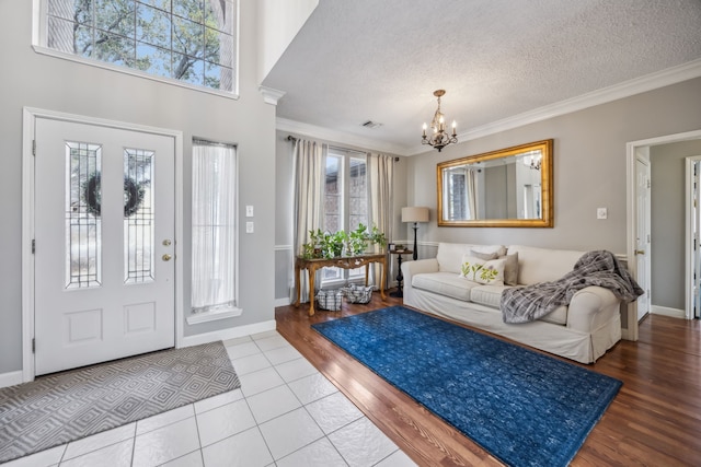 entryway with an inviting chandelier, crown molding, a wealth of natural light, and a textured ceiling