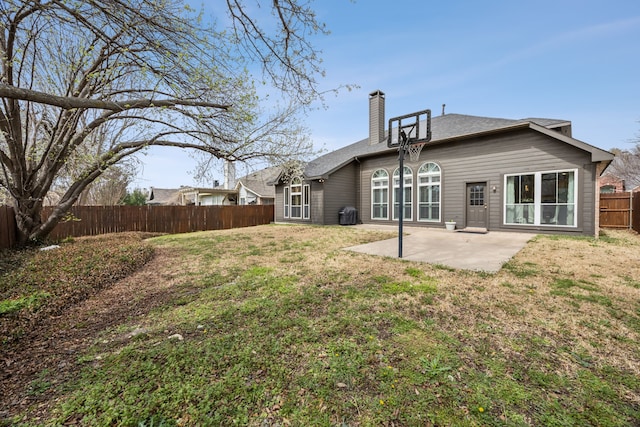 rear view of house with a patio, a lawn, a fenced backyard, and a chimney