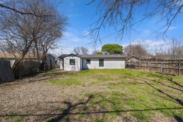 rear view of property featuring central air condition unit, a lawn, and a fenced backyard