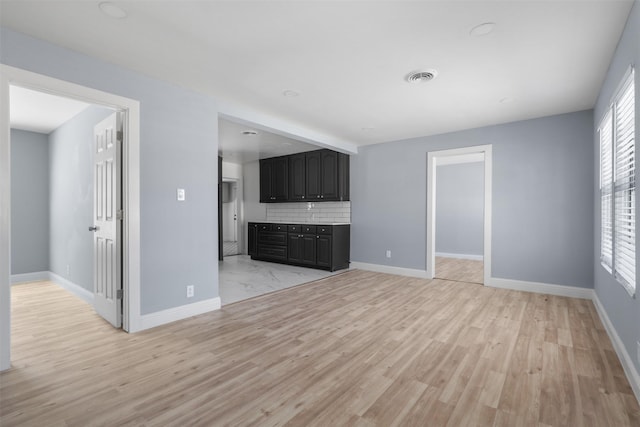 unfurnished living room featuring light wood-type flooring, baseboards, and visible vents