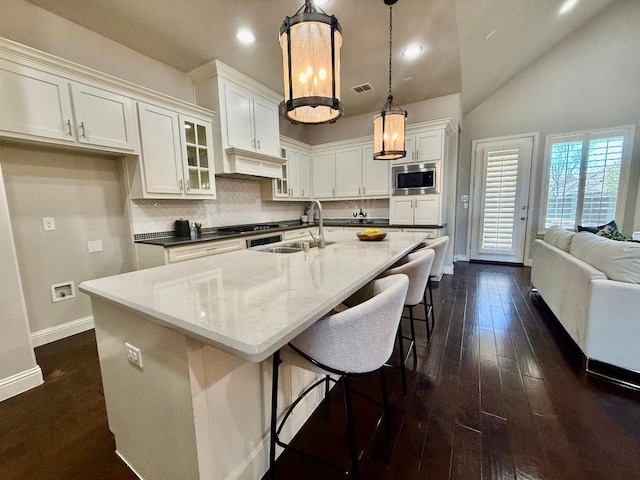 kitchen with dark wood finished floors, stainless steel microwave, white cabinets, and tasteful backsplash