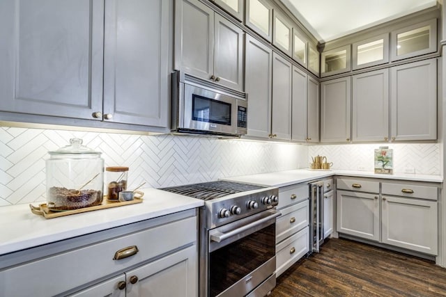 kitchen featuring tasteful backsplash, gray cabinetry, light countertops, dark wood-style floors, and stainless steel appliances