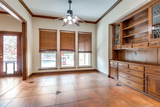 unfurnished dining area featuring ceiling fan, baseboards, ornamental molding, and light tile patterned flooring