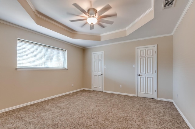 spare room with visible vents, carpet, crown molding, a raised ceiling, and ceiling fan