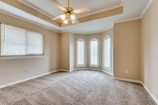 unfurnished room featuring a raised ceiling, carpet floors, ornamental molding, and a ceiling fan