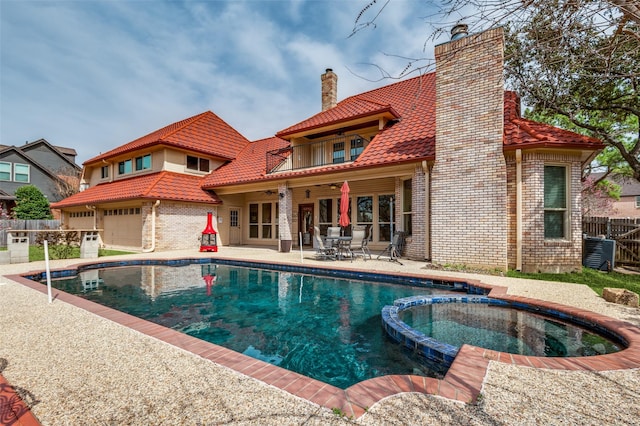 view of swimming pool featuring a patio, fence, and a pool with connected hot tub