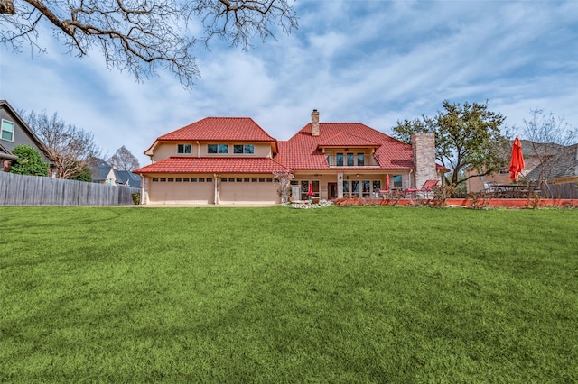 back of property featuring a tiled roof, a yard, fence, and a chimney