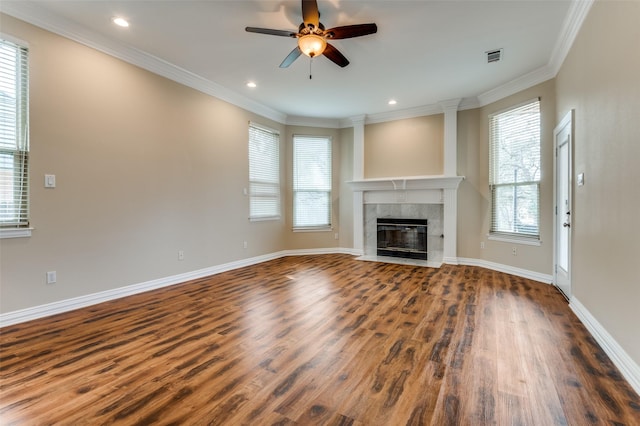 unfurnished living room with wood finished floors, baseboards, a fireplace, ceiling fan, and crown molding