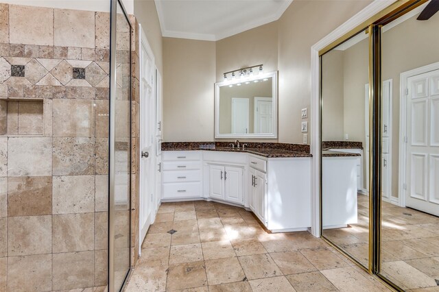 bathroom with stone tile flooring, tiled shower, vanity, and ornamental molding