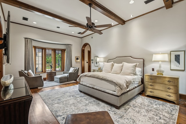 bedroom featuring wood finished floors, visible vents, beam ceiling, arched walkways, and crown molding