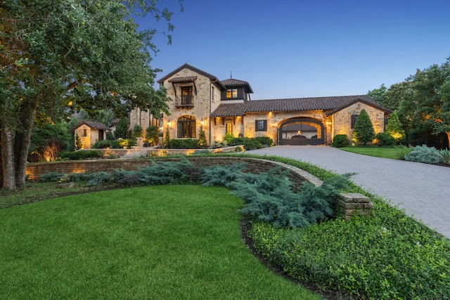 view of front facade featuring stone siding, curved driveway, a front lawn, and a tile roof